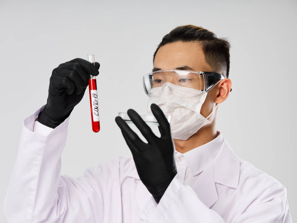Man of Asian appearance protective mask blood test examination diagnostics gray background - Foto, imagen