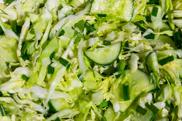 Spring vegan salad with cabbage, cucumber, green onion and parsley closeup. Food background - Фото, зображення