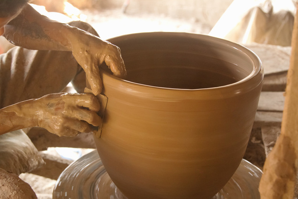 Potters handen werken op een pot op zijn aardewerk wiel - Foto, afbeelding