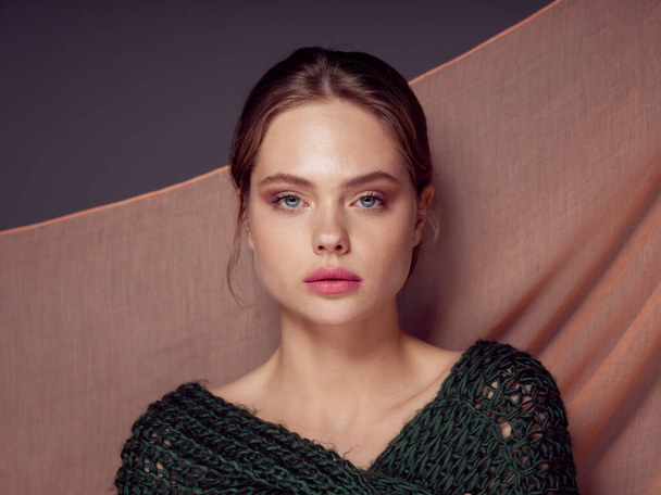 Portrait of a beautiful woman in a sweater with a beige fabric  - Photo, Image