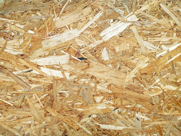 OSB planken zijn gemaakt van bruin houtsnippers geschuurd in een houten ondergrond. Bovenaanzicht van OSB hout fineer achtergrond, strakke, naadloze oppervlakken. - Foto, afbeelding