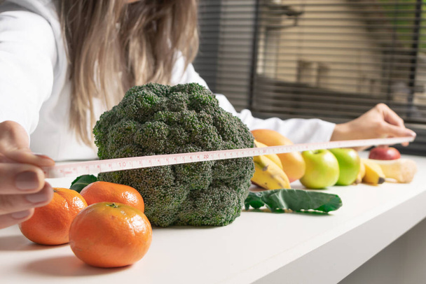 Ernährungsberaterin in ihrem Büro und zeigt gesundes Gemüse und Obst. Gesundheits- und Ernährungskonzept. Lebensstil. - Foto, Bild