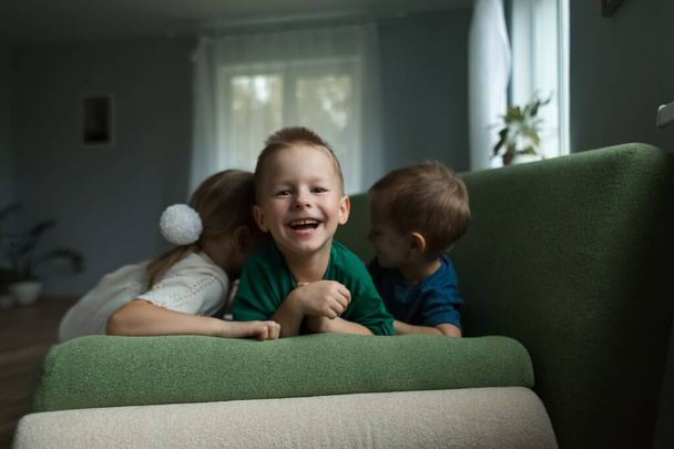 Beautiful children lying on the couch laughing at home.  - Fotó, kép