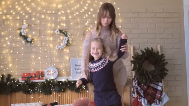 Szczęśliwa matka z córką tańcząca na łóżku, oczekująca świąt Bożego Narodzenia, radosne wakacje, piękna dekoracja na tle - Materiał filmowy, wideo