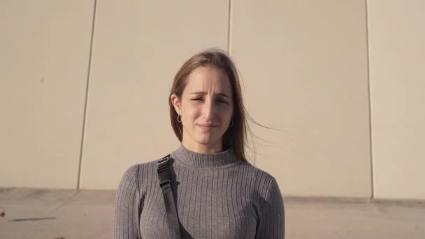 A kamerába nézek. Egy komoly spanyol fiatal nő portréja, amint egy szürke fal előtt áll.. - Felvétel, videó