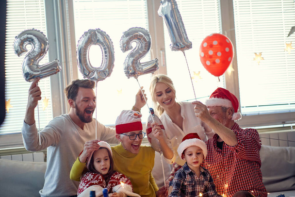Alegre familia divirtiéndose en la fiesta de fin de año en casa en un ambiente festivo. Año Nuevo, vacaciones, tiempo en familia juntos - Foto, imagen