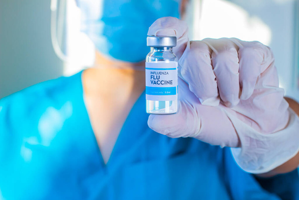 Un operatore sanitario che detiene una bottiglia di vaccino Covid-19, Coronavirus o SARS-CoV-2 su una fiala sterile trasparente con etichetta bianca e blu un globo bianco - Foto, immagini