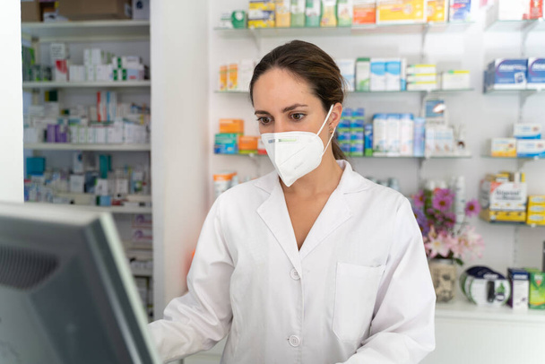 jeune jolie fille pharmacien consulte des médicaments sur son ordinateur avant - Photo, image