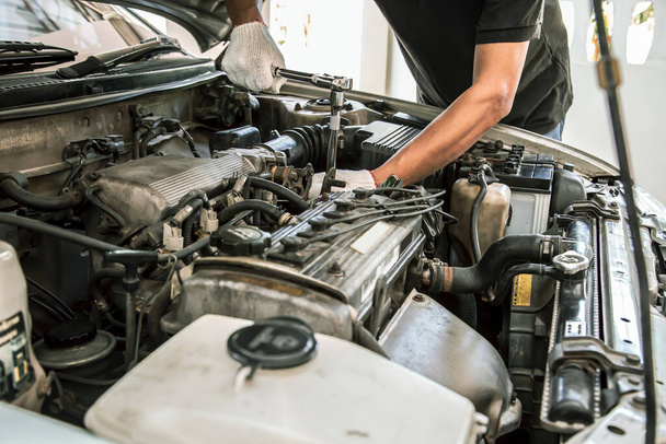 Nahaufnahme Hände des Automechanikers verwenden den Schraubenschlüssel, um einen Automotor in der Autowerkstatt zu reparieren. Konzepte der Autopflege Reparatur und Dienstleistungen. - Foto, Bild