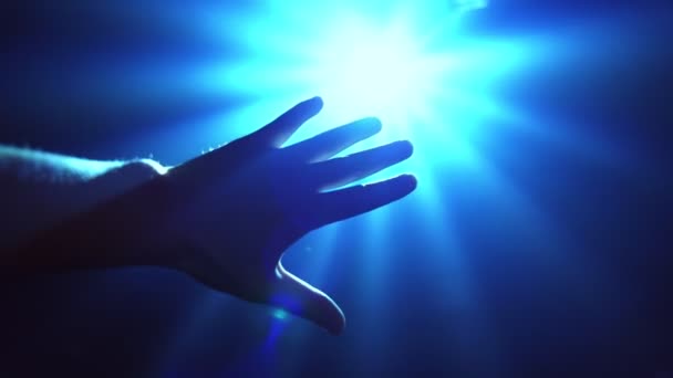 Ruka natahuje ruku, aby zakryla zářící bodové světlo - Záběry, video