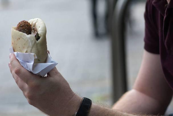 Egy ember kezében egy pitakenyér Falafellel, egy tipikus közel-keleti étel, mélyen sült golyók őrölt csicseriborsóból. Tel Aviv, Izrael - Fotó, kép
