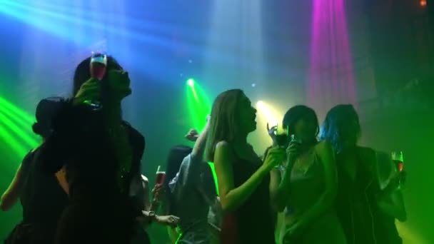 Grupo de personas bailan en discoteca al ritmo de la música de DJ en el escenario - Metraje, vídeo