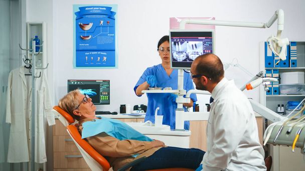 Arzt zeigt auf digitalen Bildschirm mit Zahnimplantaten - Foto, Bild