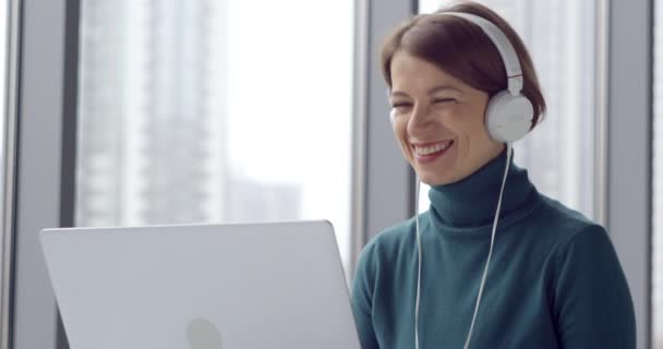Zakelijke vrouw werkt op een laptop in een koptelefoon in een online conferentie. - Video