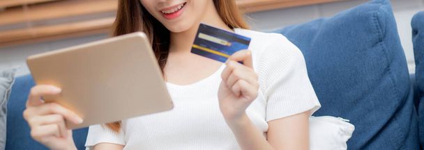 Tablet bilgisayar satın alma ve ödeme ile kredi kartı alışverişi yapan Asyalı genç bir kadının eli, banka kartı satın alma veya banka kartı kullanımı, e-ticaret konsepti, afiş web sitesi. - Fotoğraf, Görsel