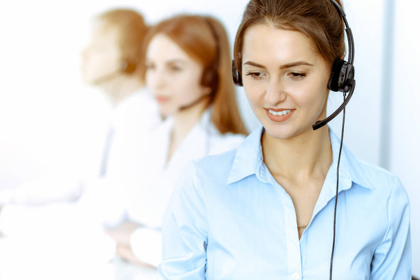 Call center. Focus on beautiful business woman in headset - Foto, imagen