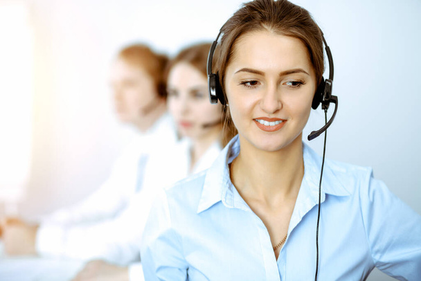 Call center. Focus on beautiful business woman in headset - Фото, изображение