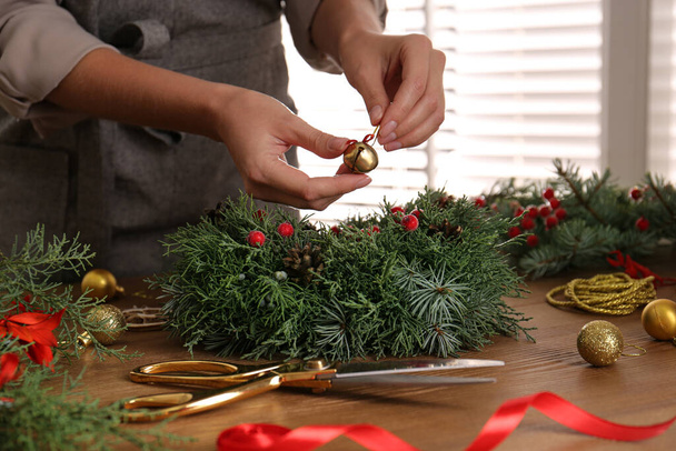 Florist making beautiful Christmas wreath at wooden table indoors, closeup - Foto, imagen