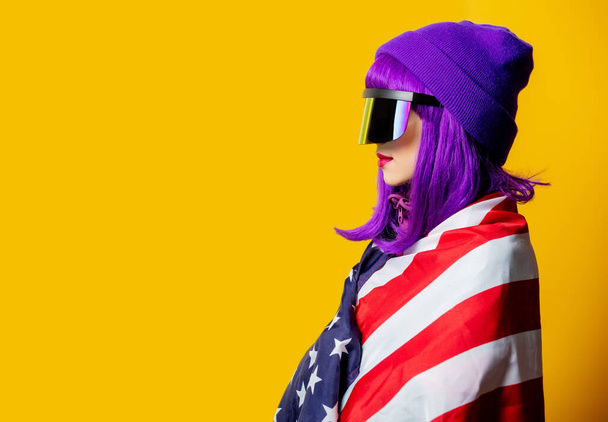 Mujer de estilo en gafas VR y chándal de los años 80 con bandera de Estados Unidos sobre fondo amarillo - Foto, Imagen