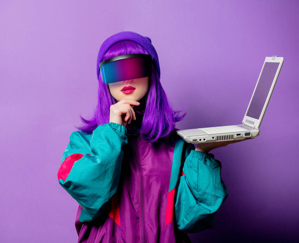 Style woman in VR glasses and 80s tracksuit with laptop on violet background - Φωτογραφία, εικόνα
