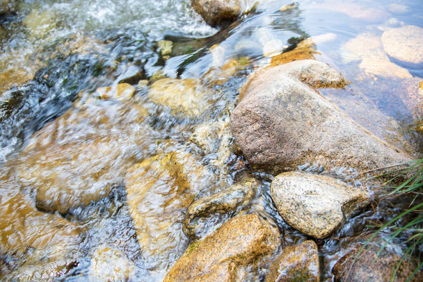красивые детали блестящей прозрачной воды, текущей по скалам в русле реки - Фото, изображение