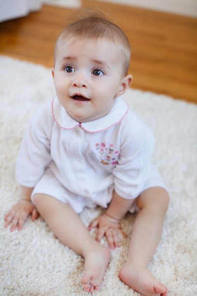 Portret van een klein meisje, zittend op de vloer - Foto, afbeelding