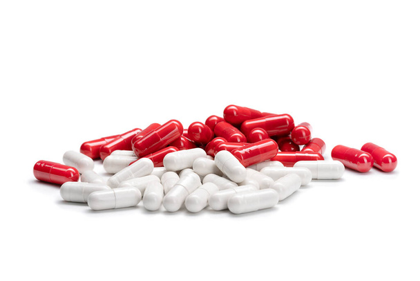 Крупный план груды красного и белого цвета таблетки или капсулы на изолированном белом фоне. Селективный фокус. - Фото, изображение
