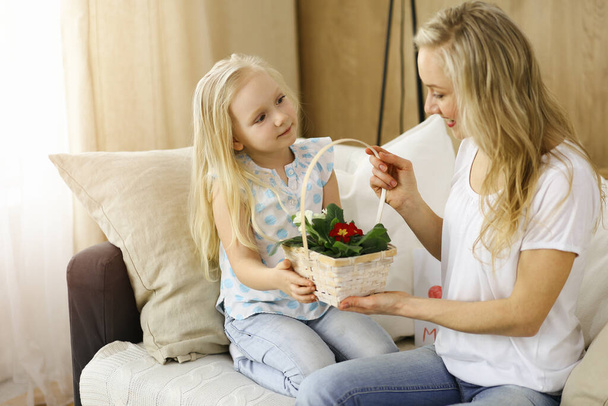 Happy mother day. Child daughter congratulates mom and gives her basket of spring flowers. Family concept - Фото, зображення