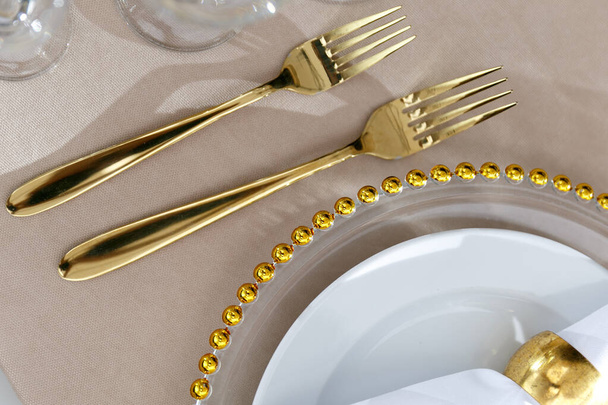Свадебные украшения. Тарелки белые с золотой рамой. Золотые столовые приборы. - Фото, изображение