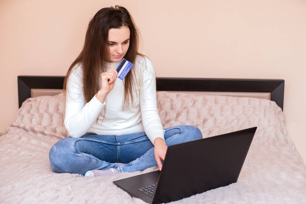 dziewczyna siedzi w Internecie wybiera, co kupić online. Zostań w domu. Rabaty i sprzedaż online. - Zdjęcie, obraz