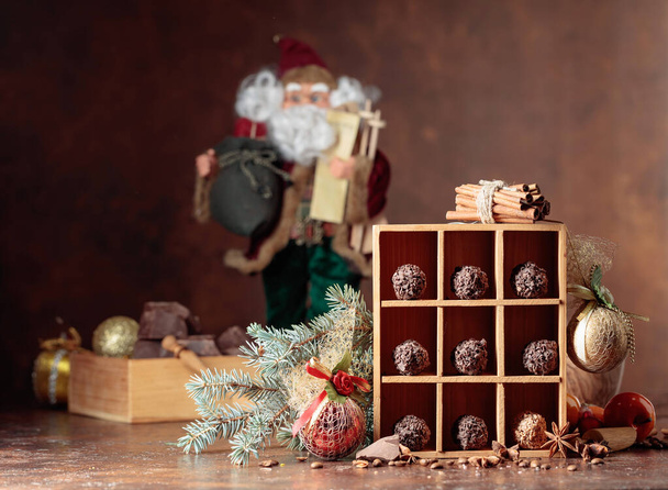Czekoladowe cukierki i świąteczne dekoracje. Złamane kawałki czekolady, paluszków cynamonowych, anyżu i ziaren kawy na brązowym tle.  - Zdjęcie, obraz