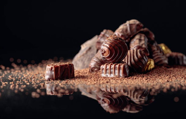 Chocolate candies on a black background sprinkled with chocolate chips. - Zdjęcie, obraz