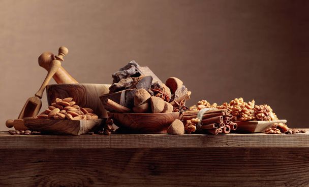 Various chocolates with ingredients. On a old wooden table candy, coffee beans, cinnamon, anise, nuts and pieces of broken black chocolate.  - Foto, immagini