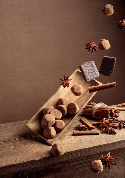 Spadające stare drewniane danie z czekoladkami, cynamonem i anyżem. Przestrzeń kopiowania. - Zdjęcie, obraz