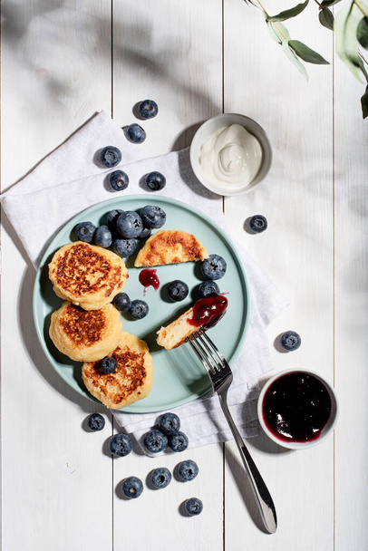 cottage cheese pancakes with sour cream, blueberry jam and blueberries top view flat lay, hard light - Φωτογραφία, εικόνα