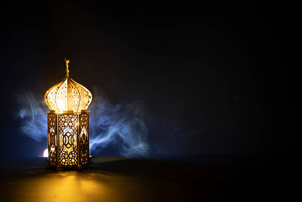 Ornamental Arabic lantern with burning candle glowing at night and glittering golden bokeh lights. Festive greeting card for Muslim holy month Ramadan Kareem. - Fotó, kép
