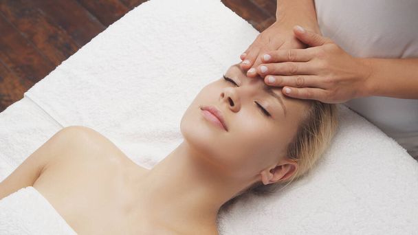 Young, beautiful and healthy woman in massaging salon. Traditional face massage therapy and skin care treatments. - Фото, зображення