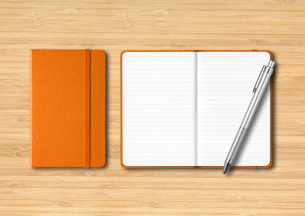 Orange closed and open lined notebooks with a pen. Mockup isolated on wooden background - Foto, Imagem