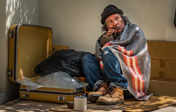 ホームレスの男は、喜びと空腹のために通行人から顔を受け取ります。彼は19の流行病のため歩道に住んでいます. - 写真・画像