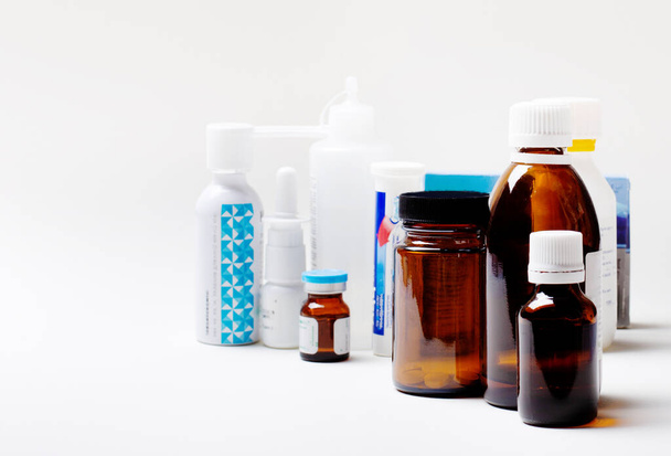 A group of glass bottles for medicines on the background of packages of medicines. Defocus. Medical concept - Photo, Image