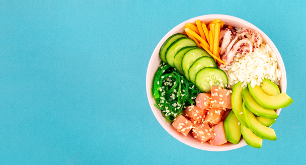 Poke kasesi, geleneksel Hawaii ve Japon çiğ balık salatası, deniz yosunu, pirinç, somon, salatalık ve avokado. Mavi bir arka planda yemek çubukları ve susam tohumlarıyla. Genel giderler, kopyalama uzayı. Düz - Fotoğraf, Görsel