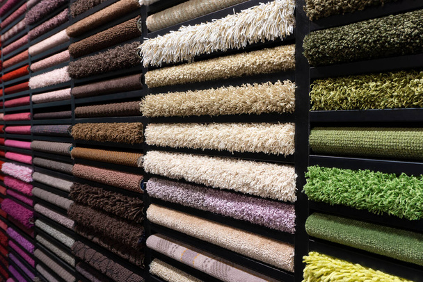 Campioni di tappeti di diversi colori su uno stand in un negozio o di produzione. Campioni di tappeti multicolori sul pavimento - Foto, immagini