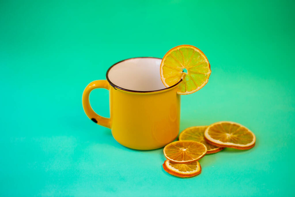 tasse jaune avec thé de Noël à la cannelle et orange séchée sur fond turquoise - Photo, image