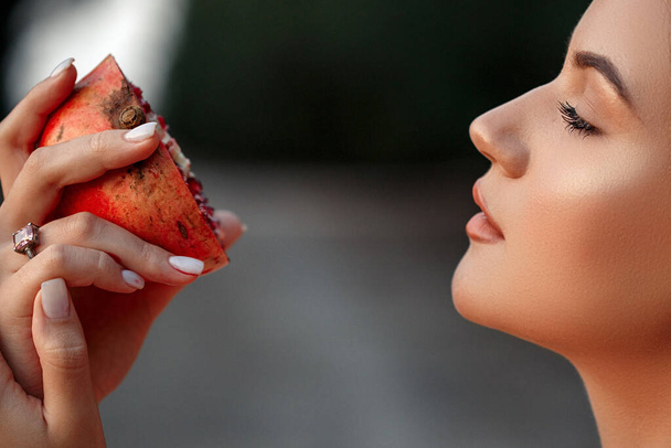 Nahaufnahme eines jungen schönen Mädchens mit einem Granatapfel in der Hand. flache DOF. Selektiver Fokus. - Foto, Bild