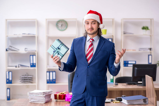 Noel arifesinde ofiste çalışan genç bir erkek işçi. - Fotoğraf, Görsel