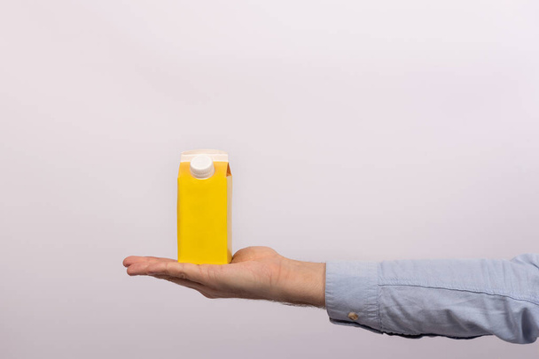 Bolso de cartón amarillo en blanco con capuchón en palma para hombre. Paquete de jugo o leche. burla para arriba. - Foto, Imagen