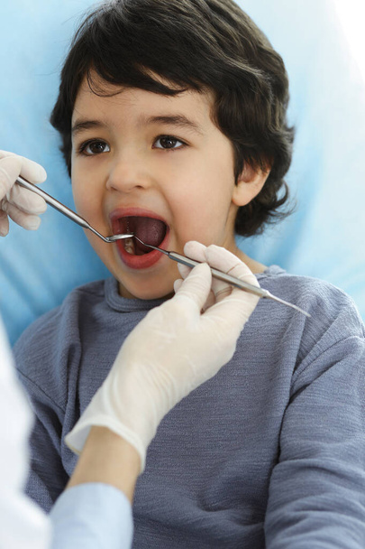 Little arab boy sitting at dental chair with open mouth during oral checking up with dentist doctor. Stomatology concept - Valokuva, kuva