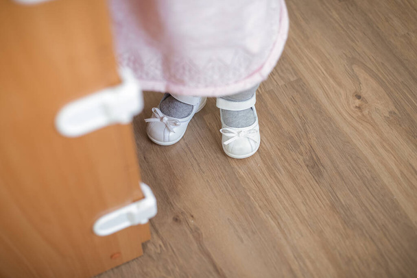 Baby feet of a one-year-old baby in white shoes - Foto, afbeelding