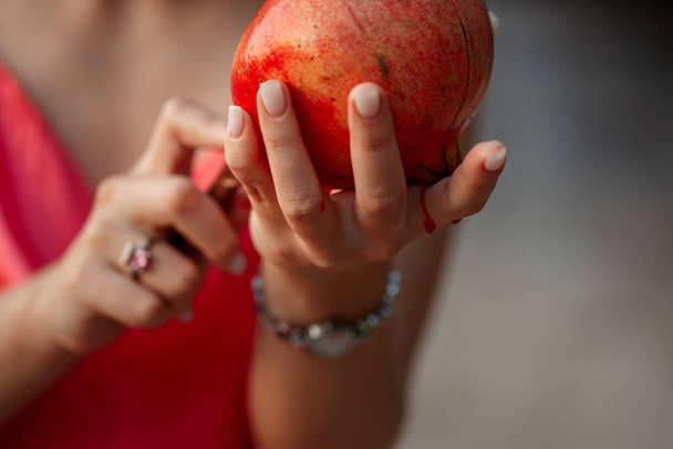 Granatapfel in den Händen einer jungen Frau. Nahaufnahme. flache DOF. Selektiver Fokus - Foto, Bild