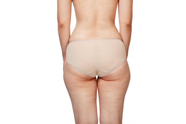 young woman in beige panties . rear view . buttocks with cellulite and overweight. on a white isolated background. concept for medicine and cosmetology. - Photo, Image